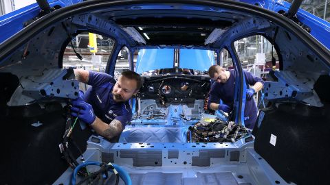Employees install cables on a production line at a BMW plant in Leipzig, Germany on October 20, 2022. Photo by Ronny Hartmann/AFP via Getty Images.
