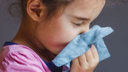 girl blowing his nose into handkerchief isolated