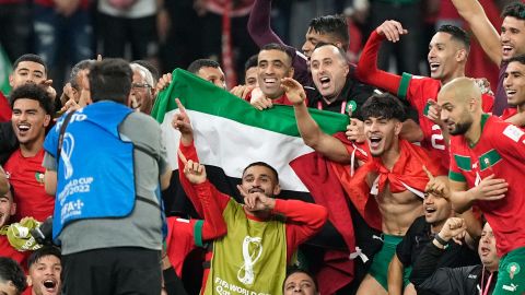 Morocco's team makes a group photo on the pitch, holding the Palestinian flag after beating Spain.