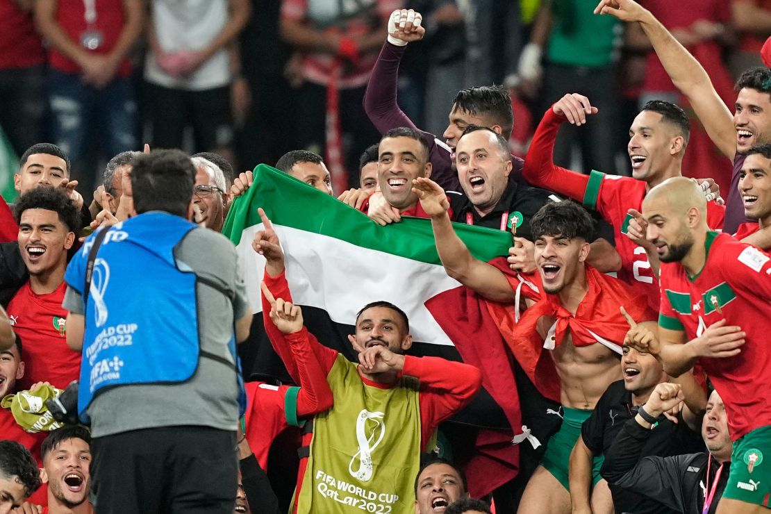 Morocco's team makes a group photo on the pitch, holding the Palestinian flag after beating Spain.