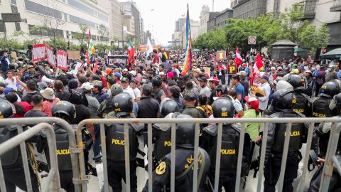 Police stand guard as people gather outside Peru's Congress after President Pedro Castillo says he will dissolve it on December 7.