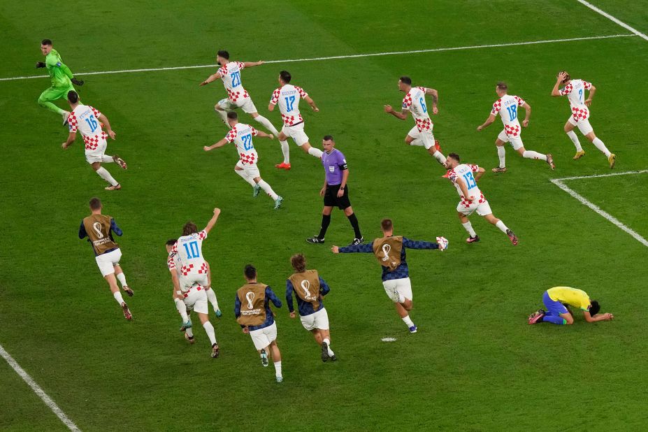Croatian players run around the field and celebrate their victory as Marquinhos, bottom right, falls to his knees.