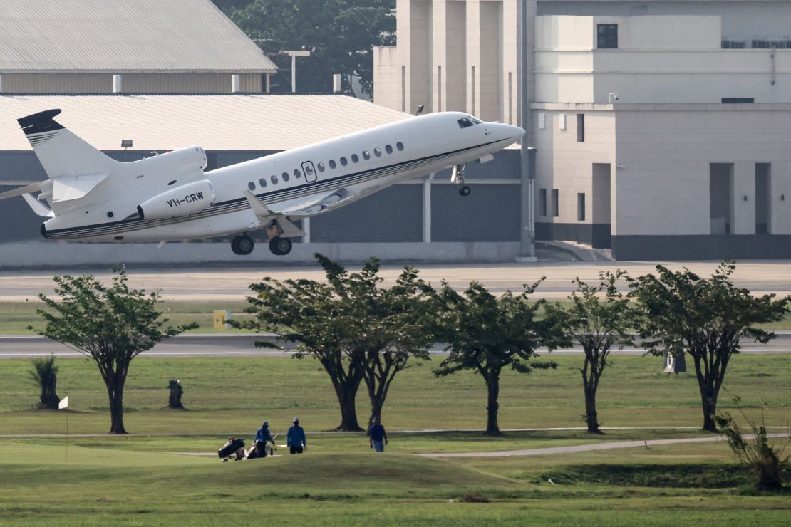 Golfers lopen over de fairways terwijl een vliegtuig opstijgt.