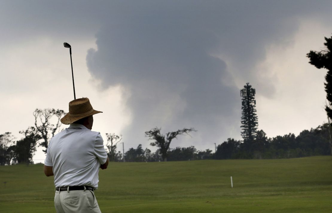 Een golfer speelt de Volcano Course terwijl as uit de topkrater van Kilauea op de achtergrond opkomt, mei 2018.