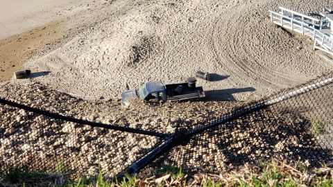 Rocks and debris pushed a pickup truck across the sand.