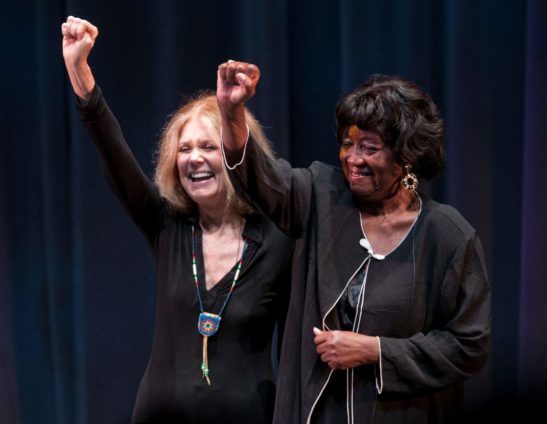 Steinem and Hughes raise their fists at speaking event in 2011, resembling a photograph taken during the height of their activism together.
