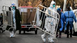Health workers wearing personal protective equipment (PPE) carry barricades inside a residential community that just opened after a lockdown due to Covid-19 coronavirus restrictions in Beijing on December 9, 2022. 