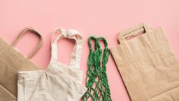 Paper bags for zero waste shopping on pink background. Space for text.