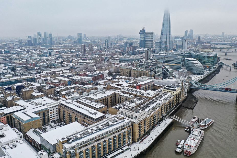 Snow-covered offices and buildings, including the Shard skyscraper, sit along the south bank of the river Thames.
