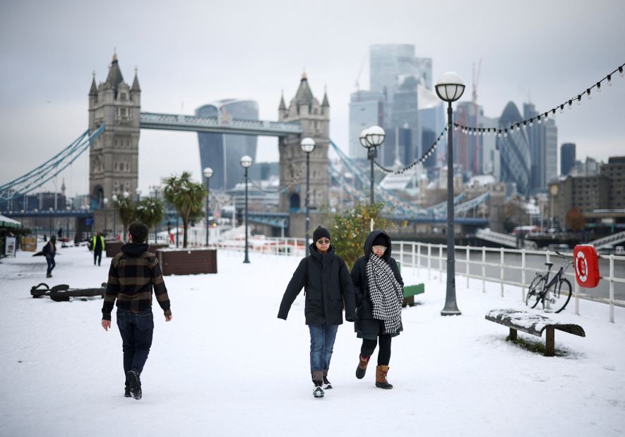 People walk on a snow-covered pathway near the Tower Bridge in London on Monday, December 12.