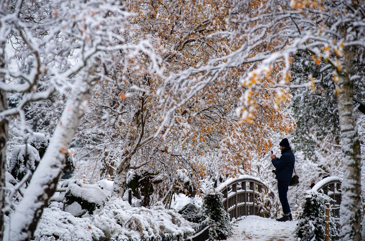 A visitor takes pictures of a snow-covered Regent's Park in London.