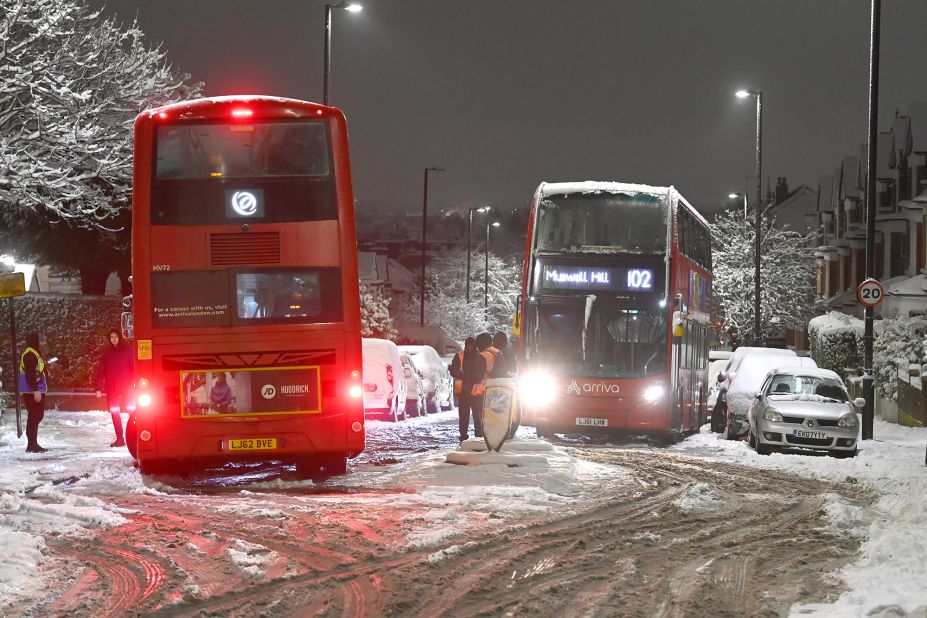 Two red London buses are seen stuck in snow in north London's Muswell Hill.