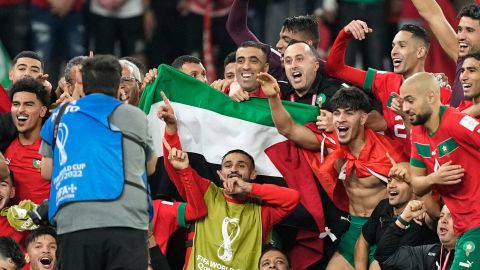 Morocco's team poses with the Palestinian flag after beating Spain on December 6. 