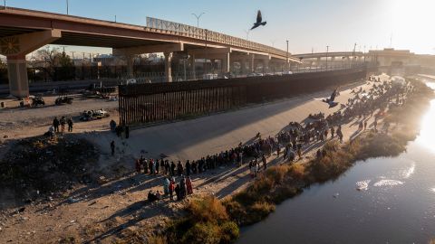 Migrants queue near the border wall after crossing the Rio Bravo to turn themselves in to US Border Patrol agents to request asylum in El Paso, Texas, as seen from Ciudad Juarez, Mexico, on December 12.  
