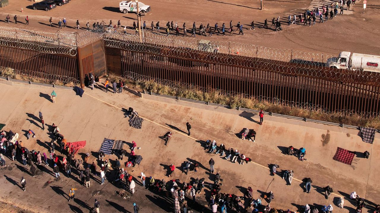 Migrants queue near the border wall after crossing the Rio Bravo river to turn themselves in to US Border Patrol agents to request asylum in El Paso, Texas, as seen from Ciudad Juarez, Mexico, on December 13, 2022. 