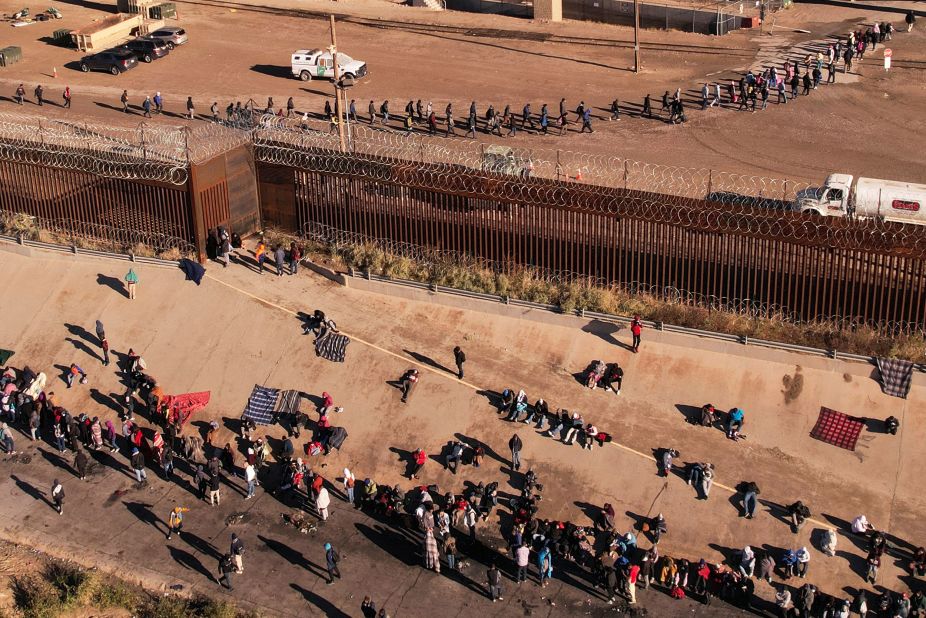 After crossing the Rio Grande, migrants line up near the border wall to turn themselves in to US Border Patrol agents on December 13.
