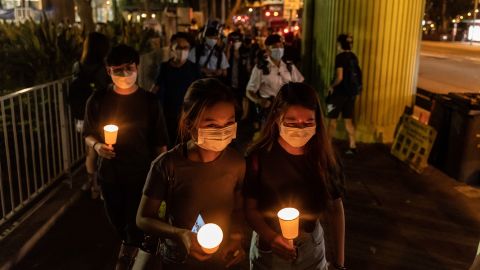 Orang-orang memegang lilin saat mereka berjalan di dekat Taman Victoria pada 4 Juni 2021 di Hong Kong. 