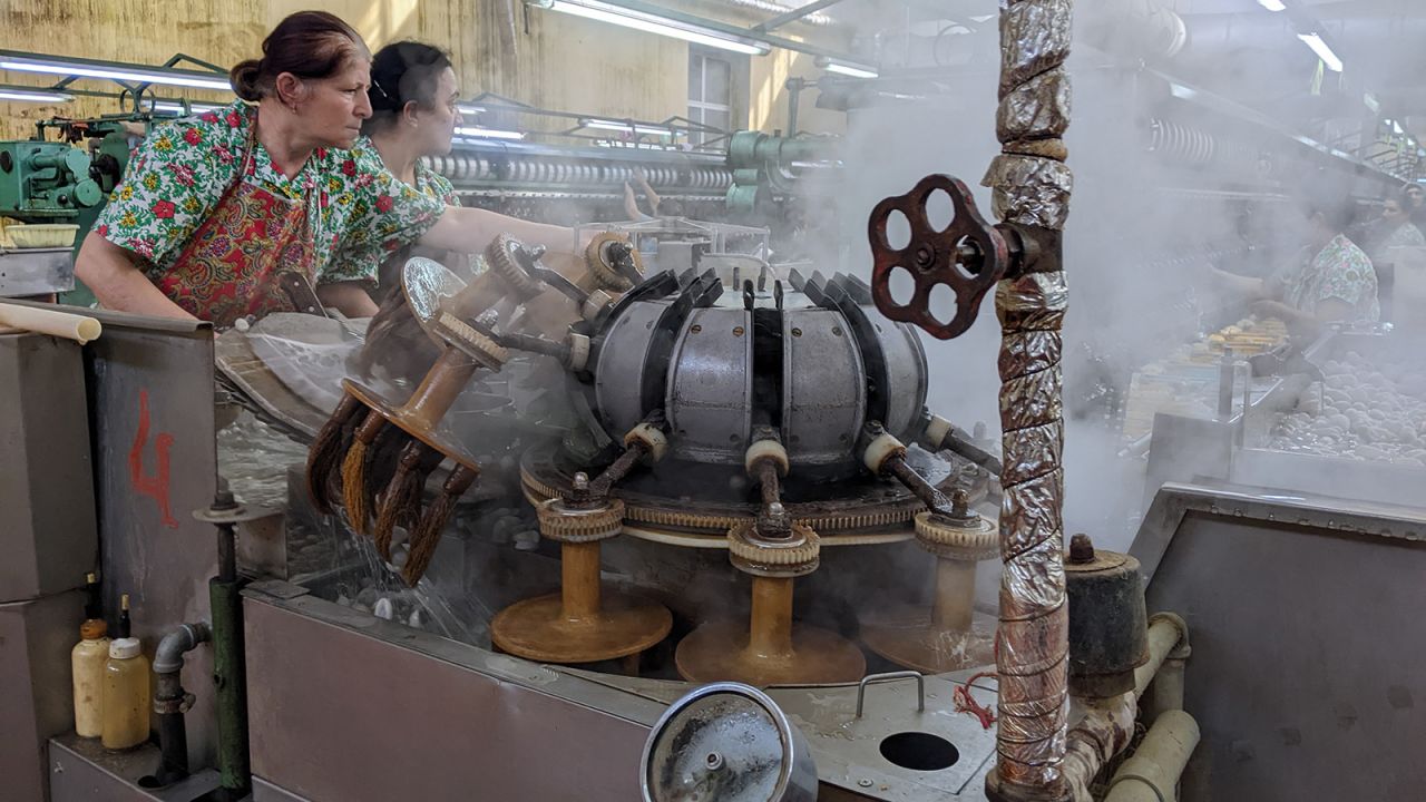 <strong>Turning cocoons into silk: </strong>The baked cocoons must be softened, their outer coatings removed by fanciful soft-brushing machines, then unraveled, spooled onto bobbins, re-spun and finally woven.
