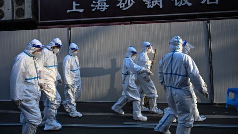 Workers in  protective clothes walk past barriers placed to close off streets in areas locked down after the detection of cases of Covid-19 in Shanghai on March 15, 2022.