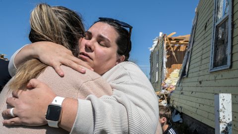 Family members embrace next to a tornado-damaged home on March 23, 2022, in Arabi, Louisiana. 