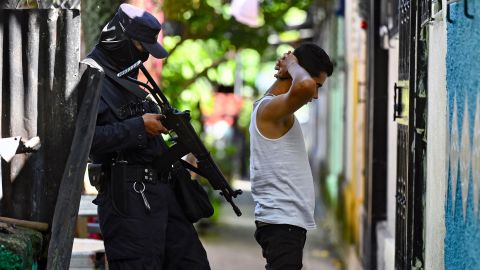 Полицейский допрашивает молодого человека во время операции по обеспечению безопасности против группового насилия в Сояпанго, к востоку от столицы Сан-Сальвадора, 16 августа 2022 года.