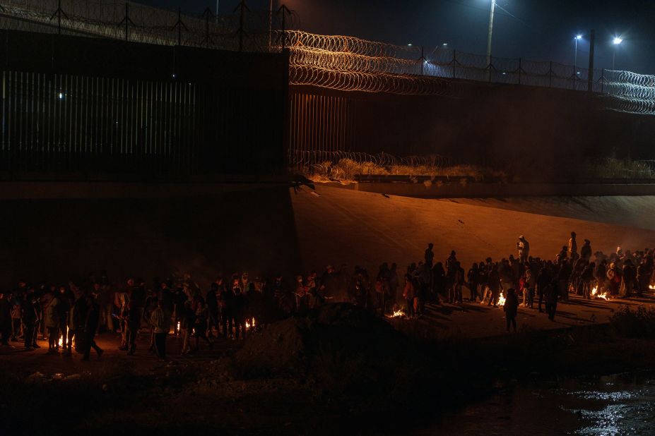 Migrants keep warm next to fires while waiting in line in El Paso on December 11.