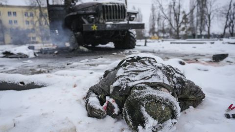 The body of a serviceman is coated in snow next to a destroyed Russian military multiple rocket launcher vehicle on the outskirts of Kharkiv, Ukraine, Friday, February 25, 2022.