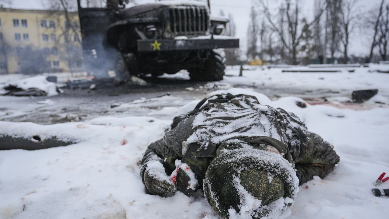 The body of a serviceman is coated in snow next to a destroyed Russian military multiple rocket launcher vehicle on the outskirts of Kharkiv, Ukraine, Friday, February 25, 2022. 