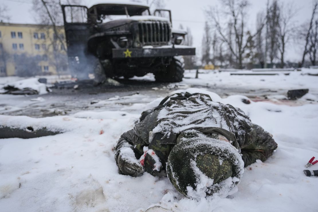 The body of a serviceman is coated in snow next to a destroyed Russian military multiple rocket launcher vehicle on the outskirts of Kharkiv, Ukraine, Friday, February 25, 2022. 