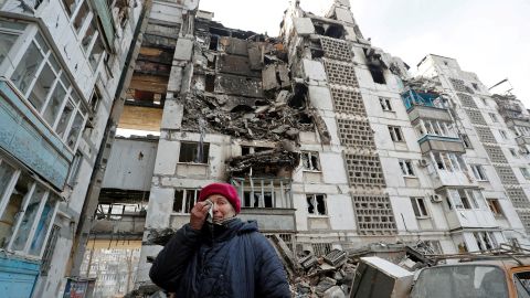 70岁的当地居民瓦伦蒂娜·德穆拉（Valentina Demura）站在她位于南部港口城市马里乌波尔的被毁公寓所在的建筑物旁边。