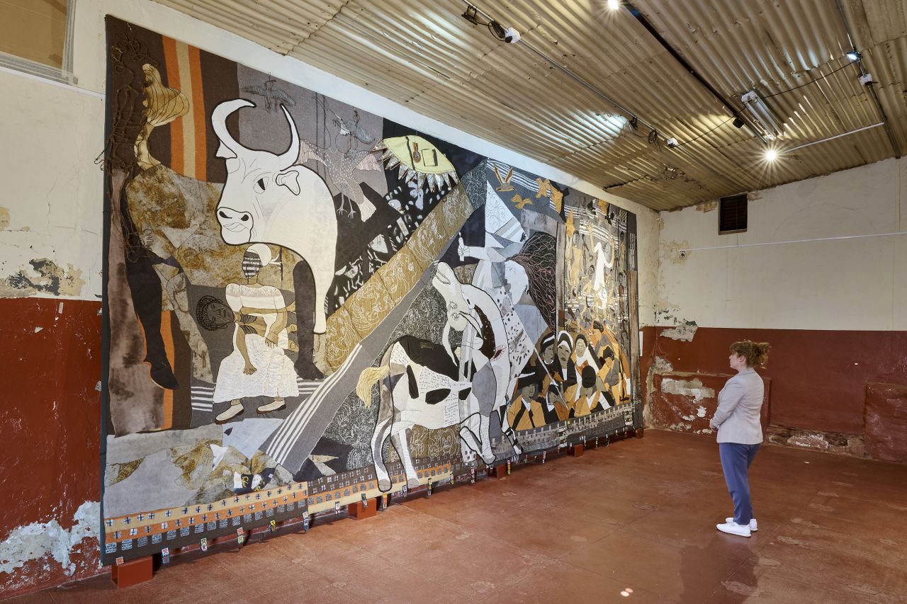 A visitor stands in front of the "Keiskamma Guernica" (2010), a 3.5x7.8-meter (11.5x26.6-foot) tapestry inspired by Pablo Picasso's 1937 painting "Guernica."