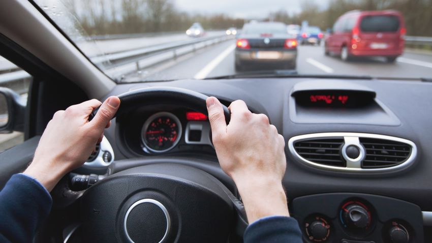 driving car on highway, close up of hands on steering wheel.