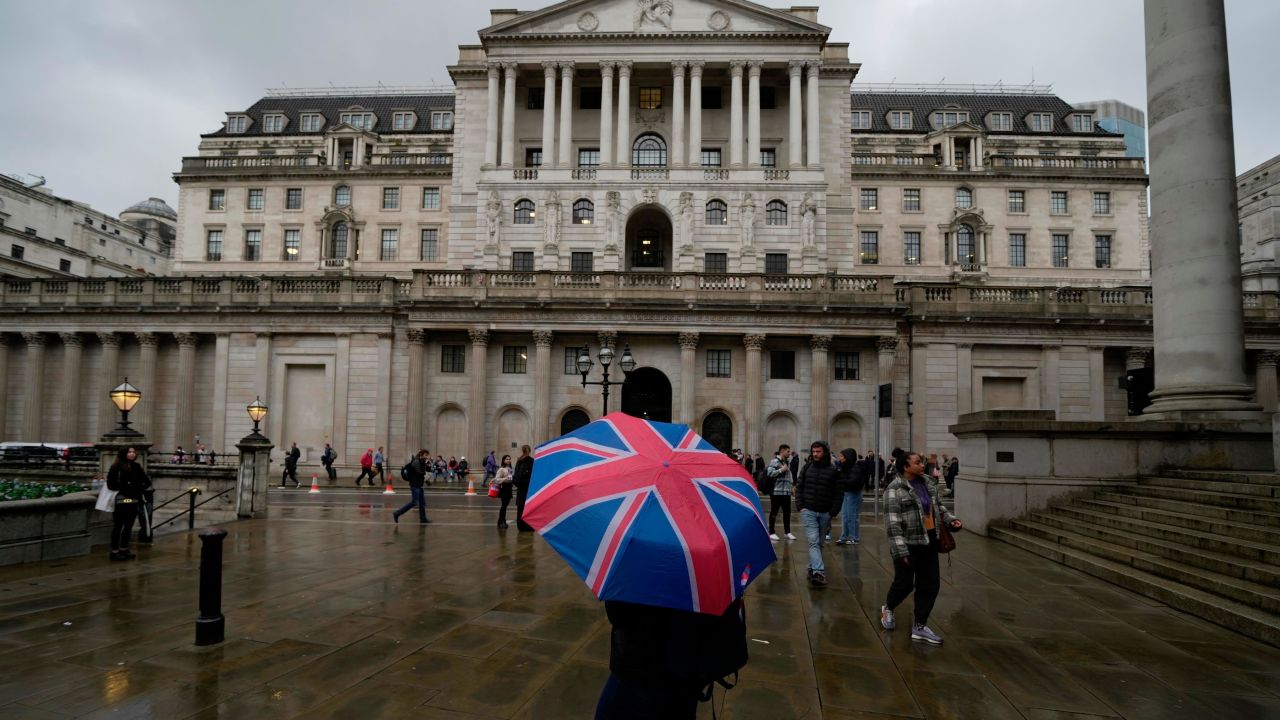 A woman with an umbrella stands in front of the Bank of England in November 2022.