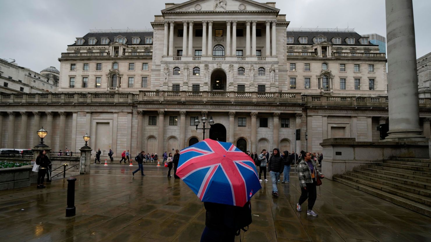 A woman with an umbrella stands in front of the Bank of England in November 2022.