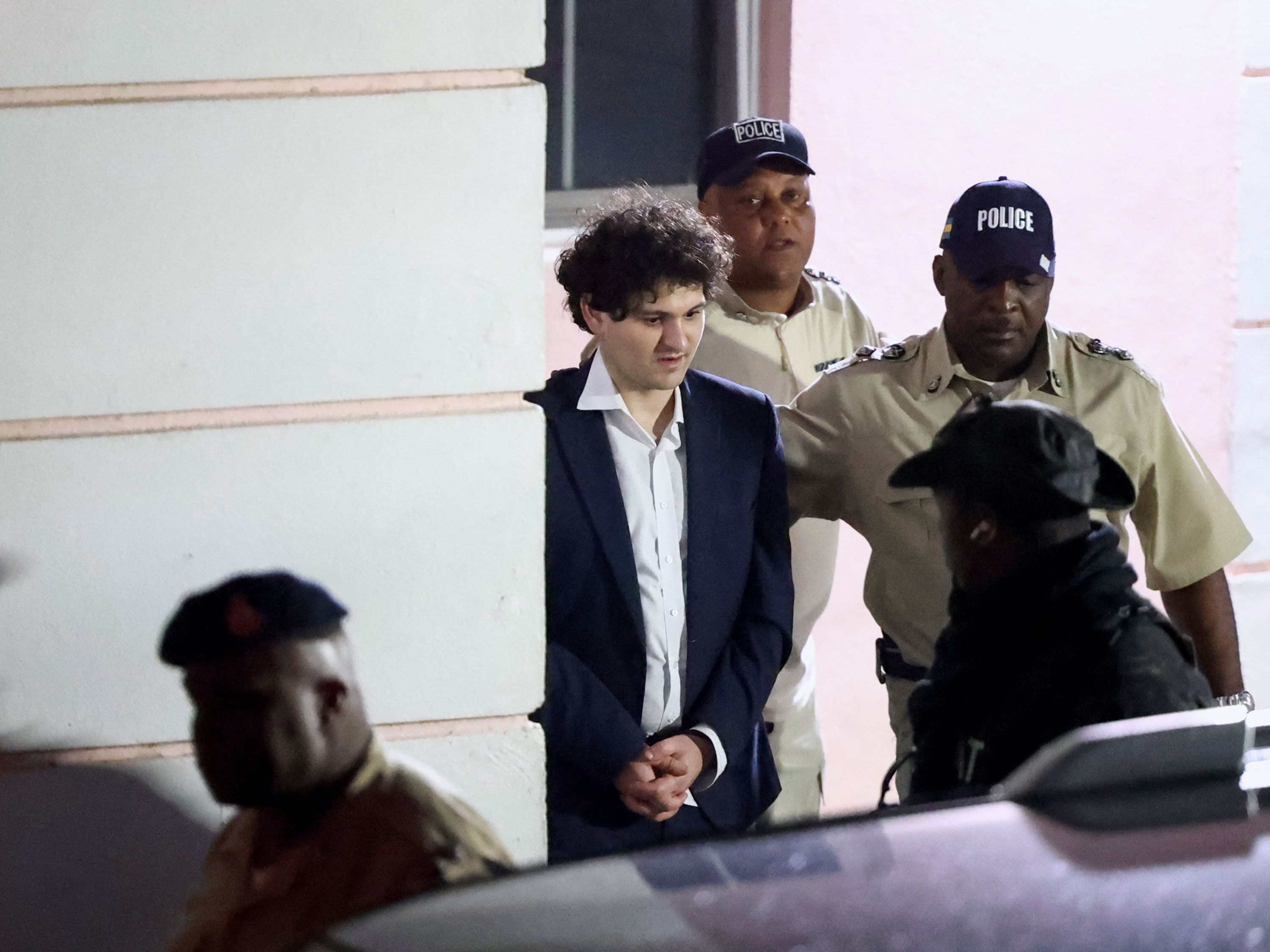 Sam Bankman-Fried, the founder of failed crypto exchange FTX, is escorted out of the Magistrate Court building in Nassau, Bahamas, on Tuesday, December 13.