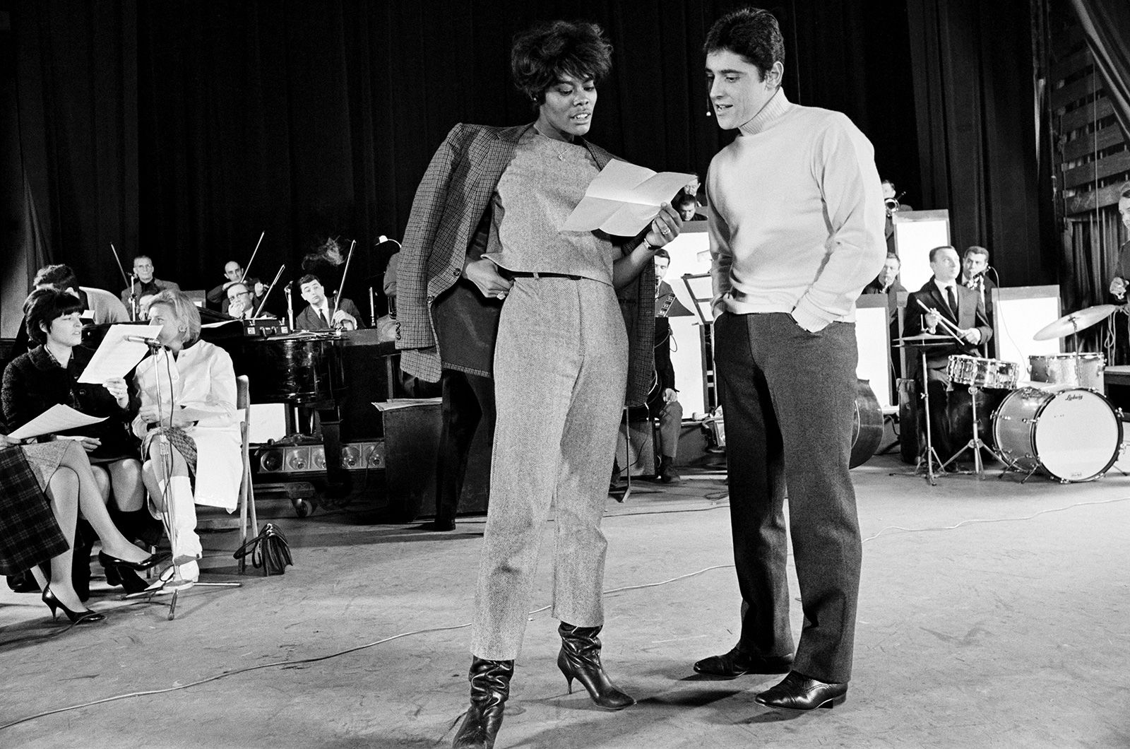 Warwick and French singer Sacha Distel review notes during rehearsals backstage in Paris in 1965.