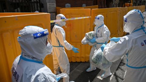 Workers in hazmat suits deliver vegetables to residents at a locked-down neighborhood in Shanghai in March.