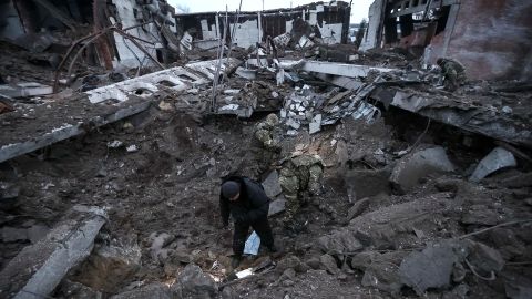 Police and investigators inspect a crater at a site of an industrial area destroyed by a Russian missile strike in Kharkiv.