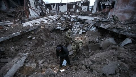 Police and investigators inspect a crater at a site of an industrial area destroyed by a Russian missile strike in Kharkiv.