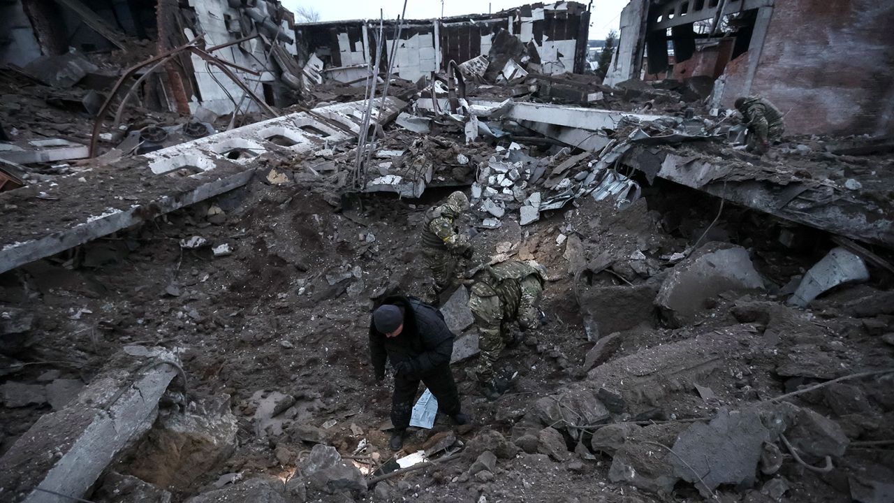 Police and investigators inspect a crater at a site of an industrial area destroyed by a Russian missile strike in Kharkiv.