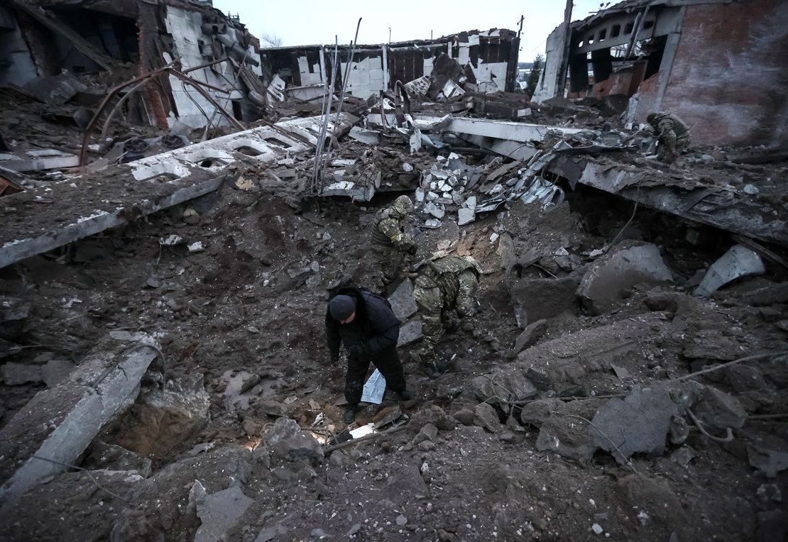 Police and investigators inspect a crater at a site of an industrial area destroyed by a Russian missile strike in Kharkiv.