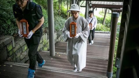 Staff and a volunteer Buddhist nun of a nonprofit organization carry the name tablets of people who died 