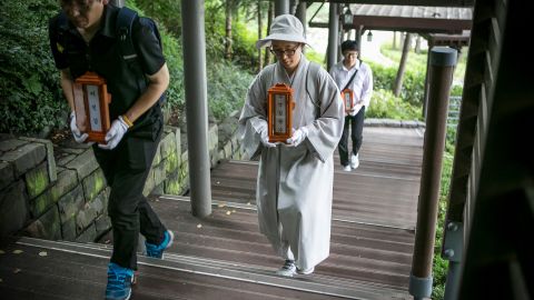 Staff and a volunteer Buddhist nun of a nonprofit organization carry the name tablets of people who died