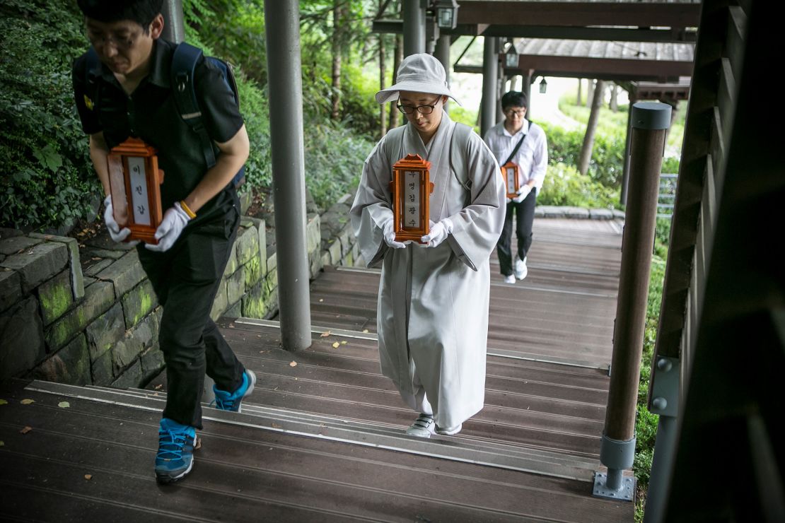 Staff and a volunteer Buddhist nun of a nonprofit organization carry the name tablets of people who died "lonely deaths" at a crematorium on June 16, 2016 in Goyang, South Korea. 