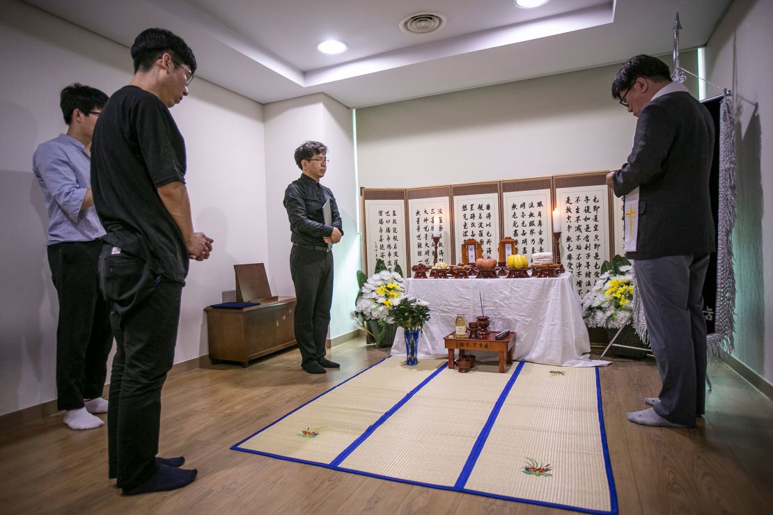 A volunteer pastor prays before a makeshift shrine for two people who died "lonely deaths," inside the waiting room of a crematoriumon on July 4, 2016 in Goyang, South Korea. 