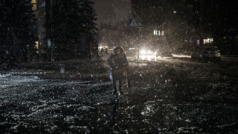 A woman crosses the street during snowfall, as power outages continue in Kyiv, Ukraine, on Friday, December 16, 2022.