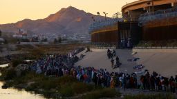Migrants queue near the border wall in El Paso to turn themselves in to Border Patrol agents and request asylum in the US.