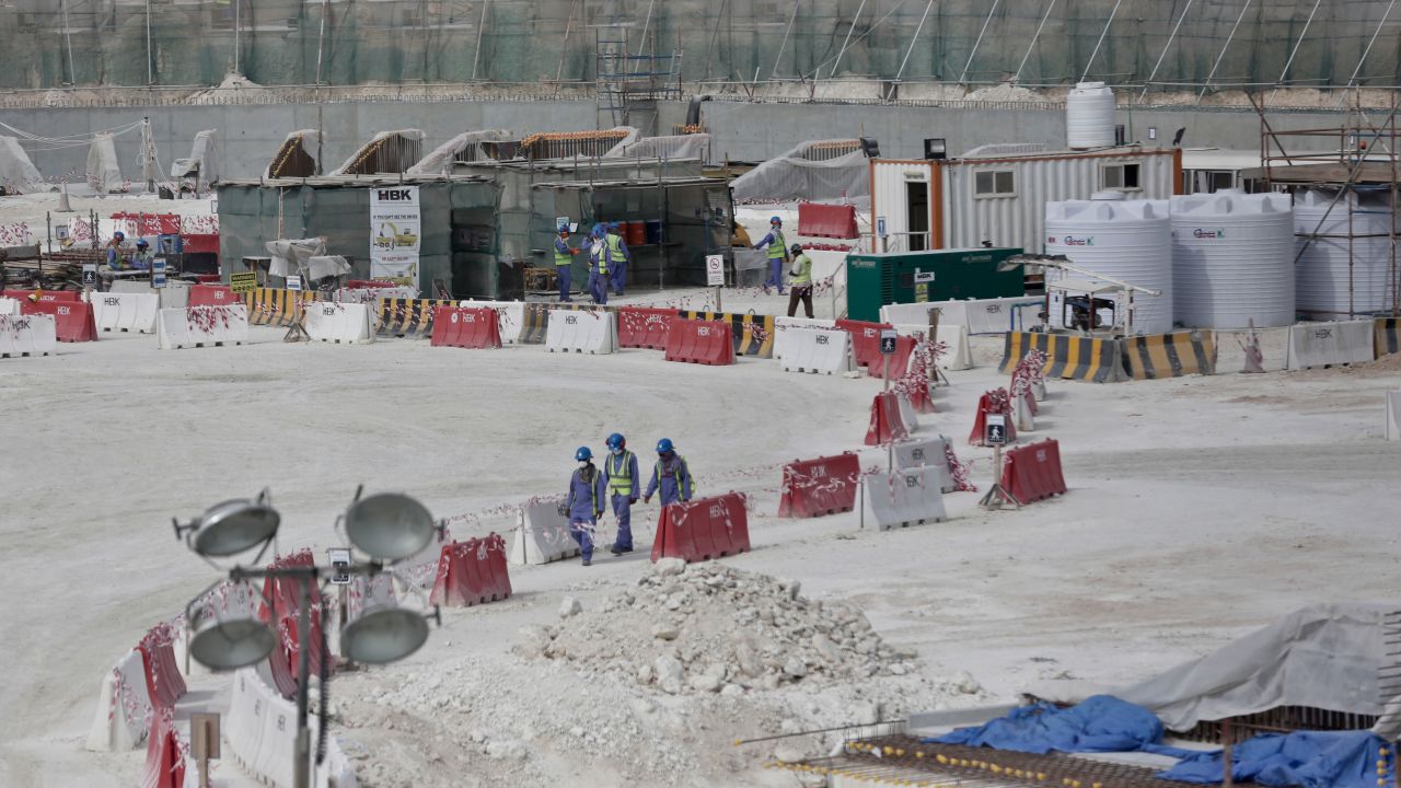 In this photo taken during a government organized media tour, foreign workers walk between safety barricades at the site of the pitch of the Al-Wakra Stadium that is under construction for the 2022 World Cup, in Doha, Qatar, Monday, May 4, 2015.