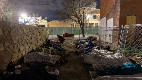 Immigrants sleep in the cold outside a bus station on December 18, 2022, in El Paso, Texas. 