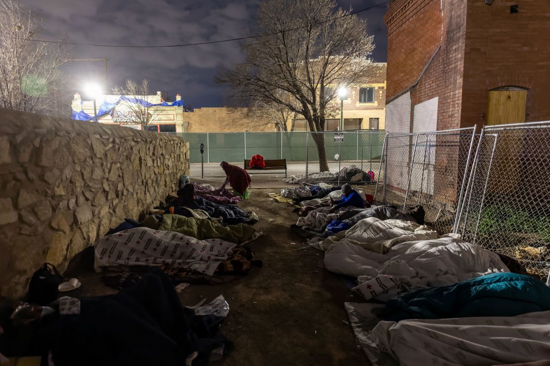 Immigrants sleep in the cold outside a bus station on December 18, 2022, in El Paso, Texas. 